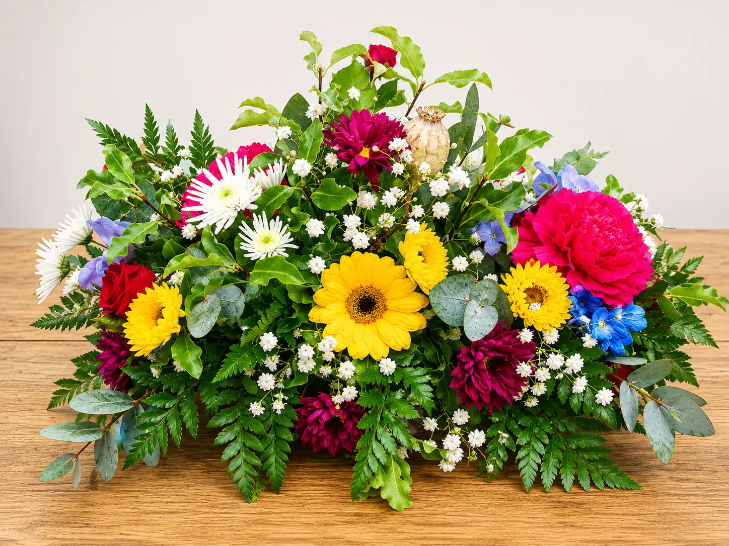 Vibrant funeral tribute with magenta carnations, yellow gerbera and white chrysanthemums
