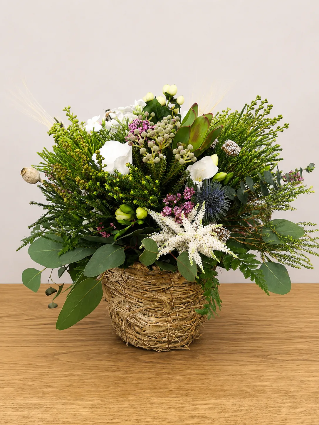 Foliage-rich basket arrangement with white flowers and purple accents