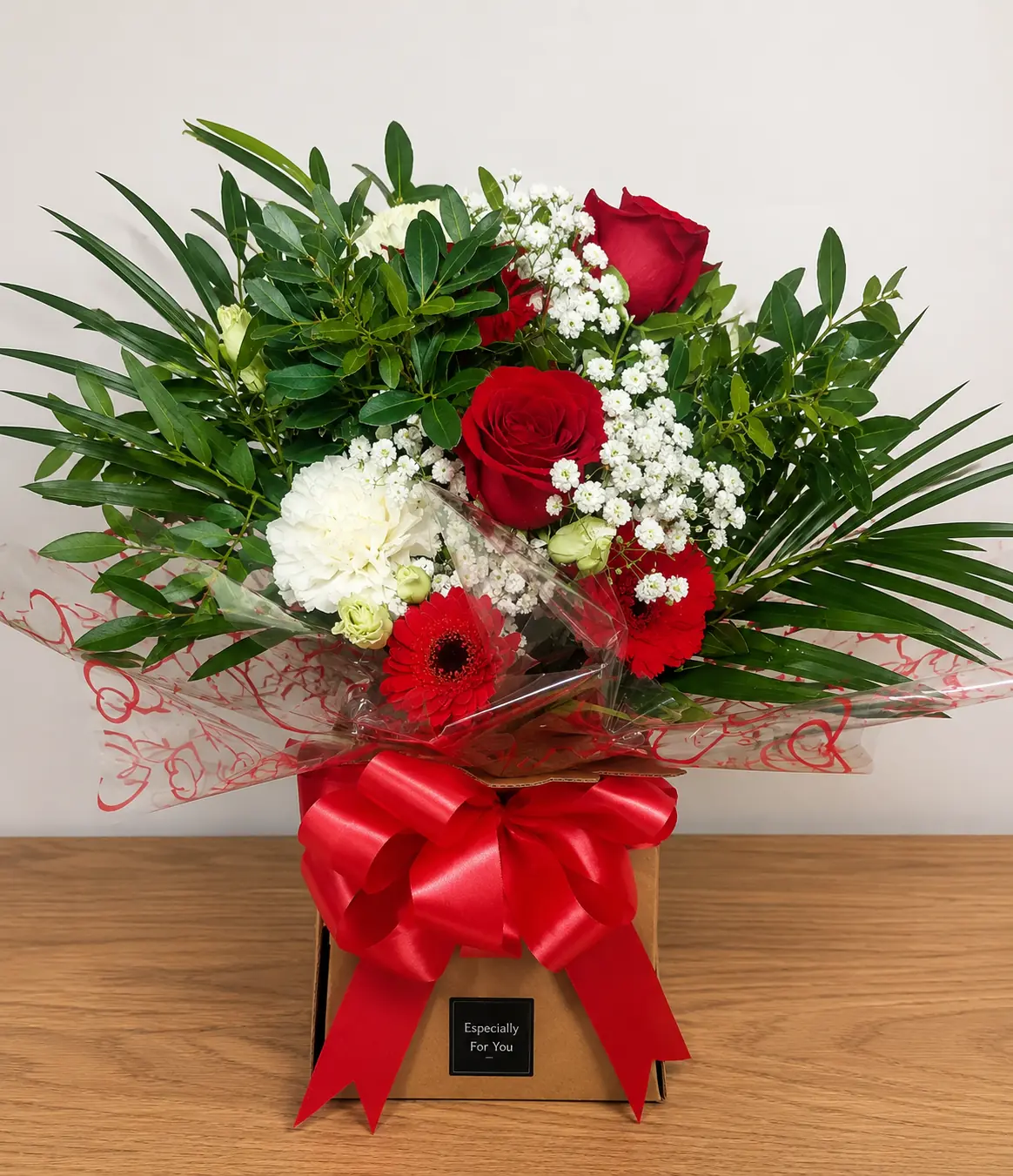 Red and white Christmas bouquet box arrangement with roses and foliage