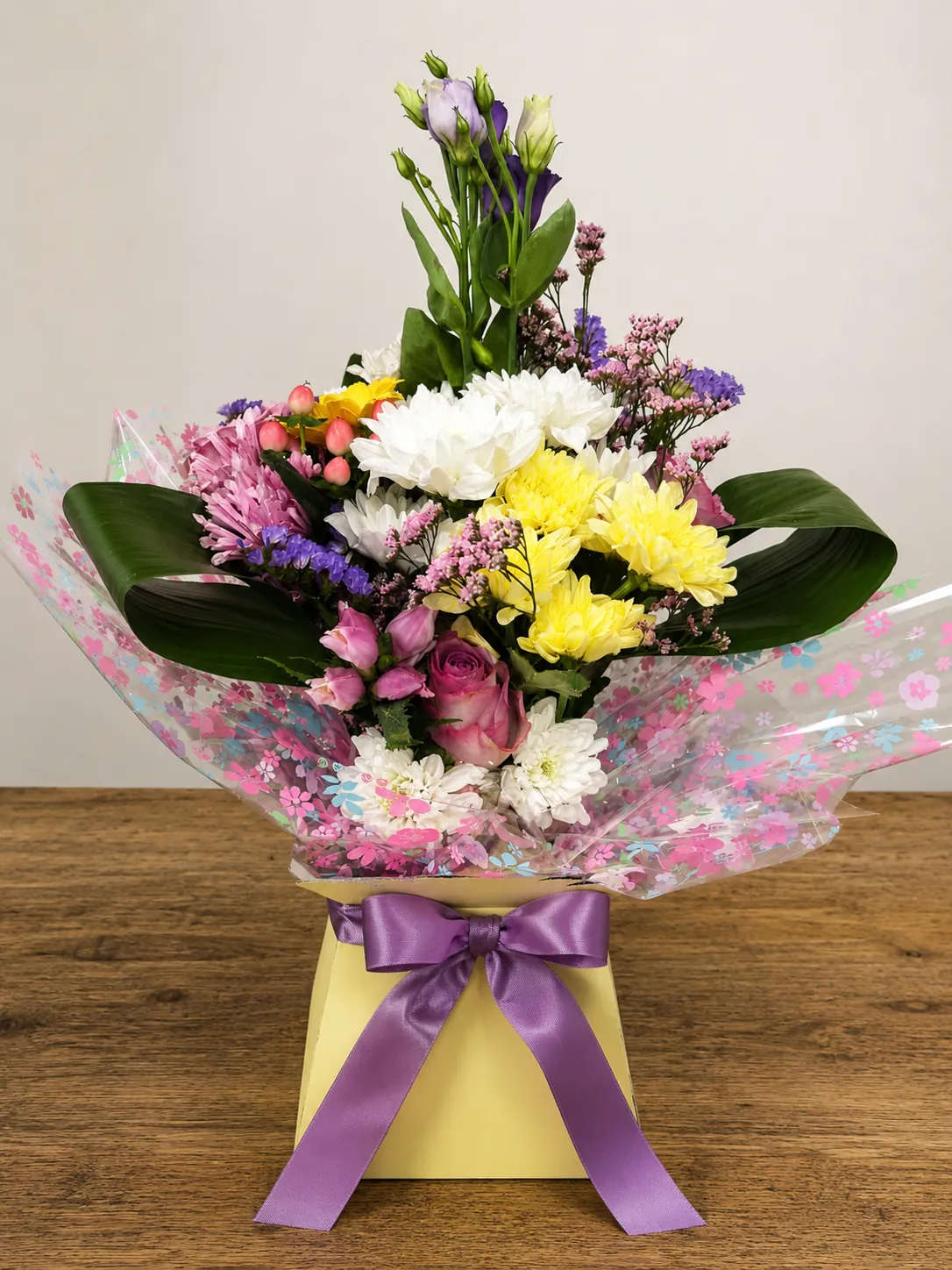 Pastel box arrangement with pink lisianthus, yellow chrysanthemum and a mauve rose in a floral wrap
