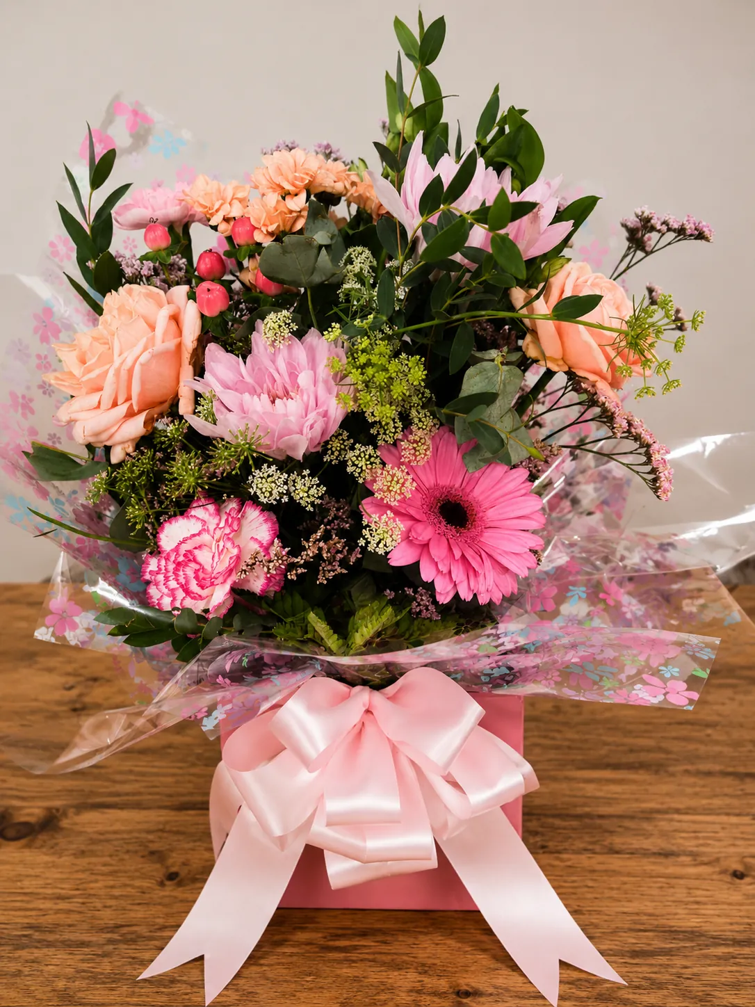 Pink box arrangement with peach roses, pink gerbera and carnations wrapped in floral cellophane