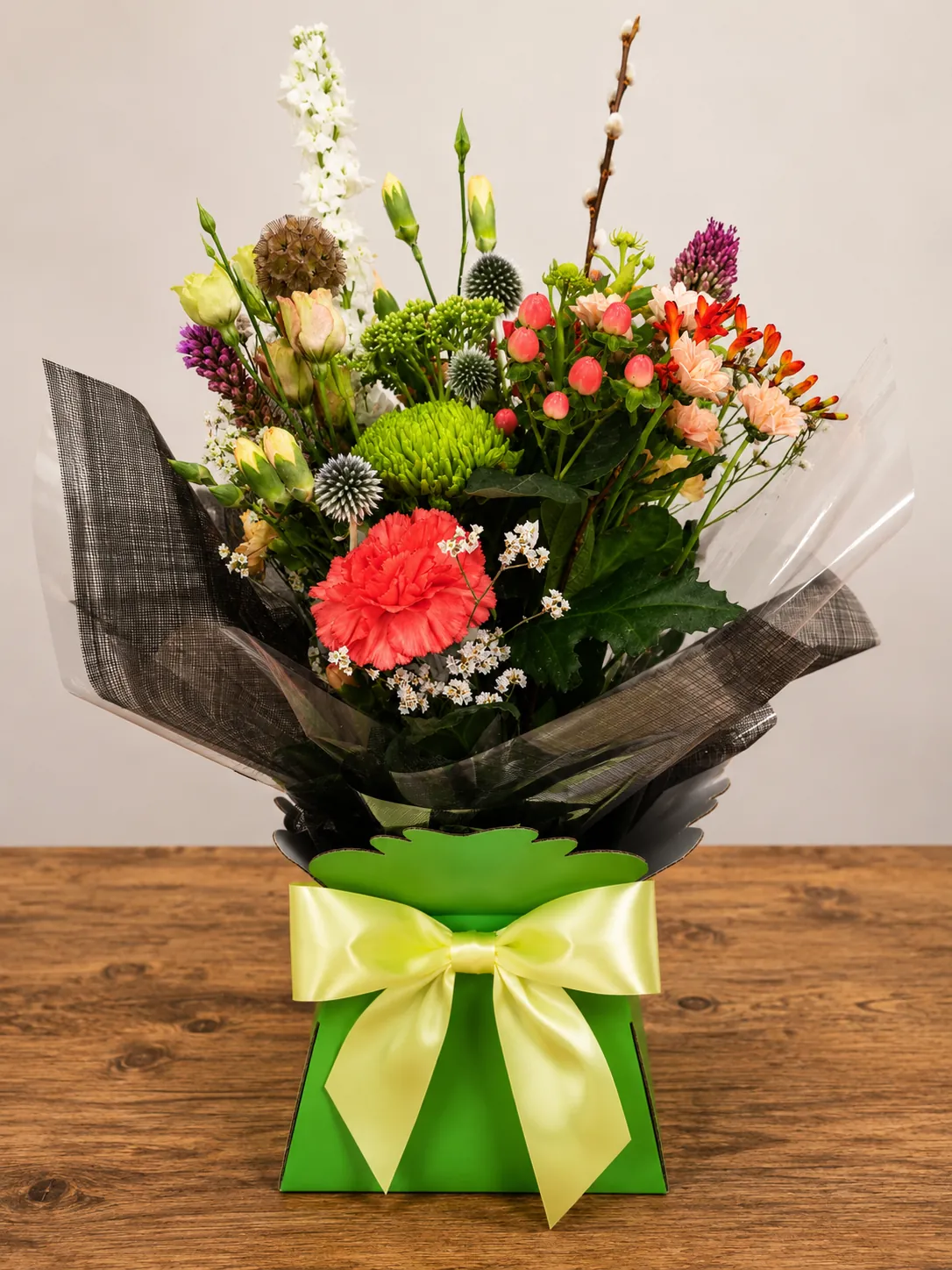 Autumn-toned box arrangement with a red carnation, green chrysanthemum and pussy willow in a lime green gift box