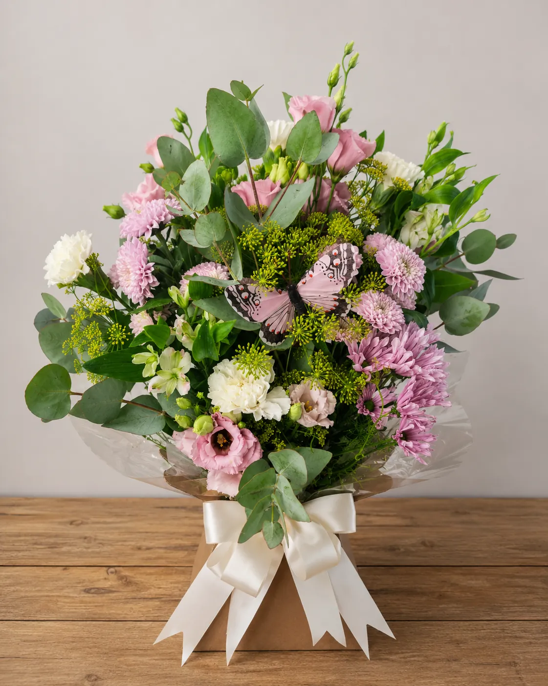 Pink and white box arrangement with a decorative butterfly pick among lisianthus and chrysanthemums, tied with an ivory bow