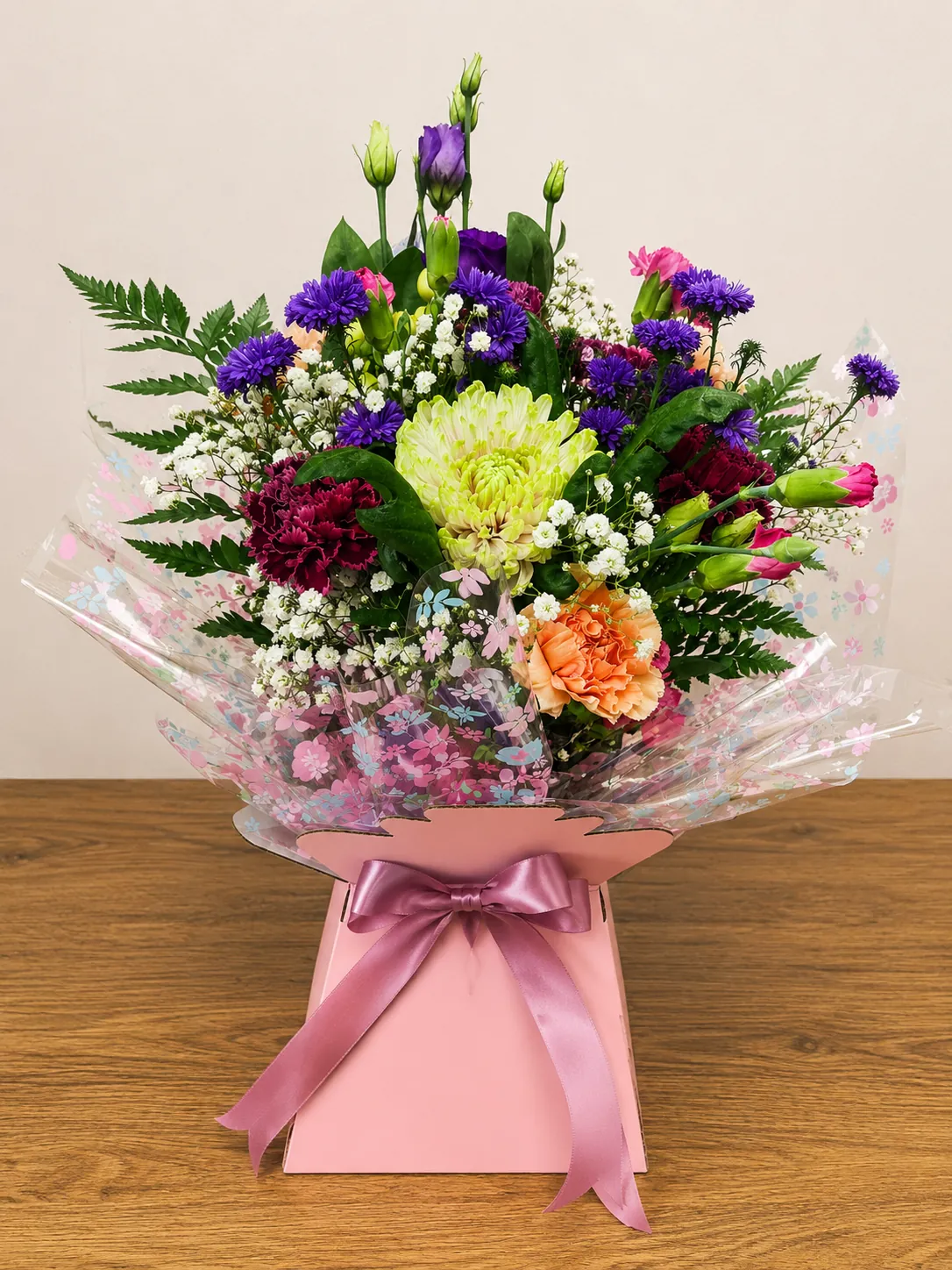 Colourful box arrangement with green chrysanthemum, burgundy carnation and orange carnation in floral cellophane