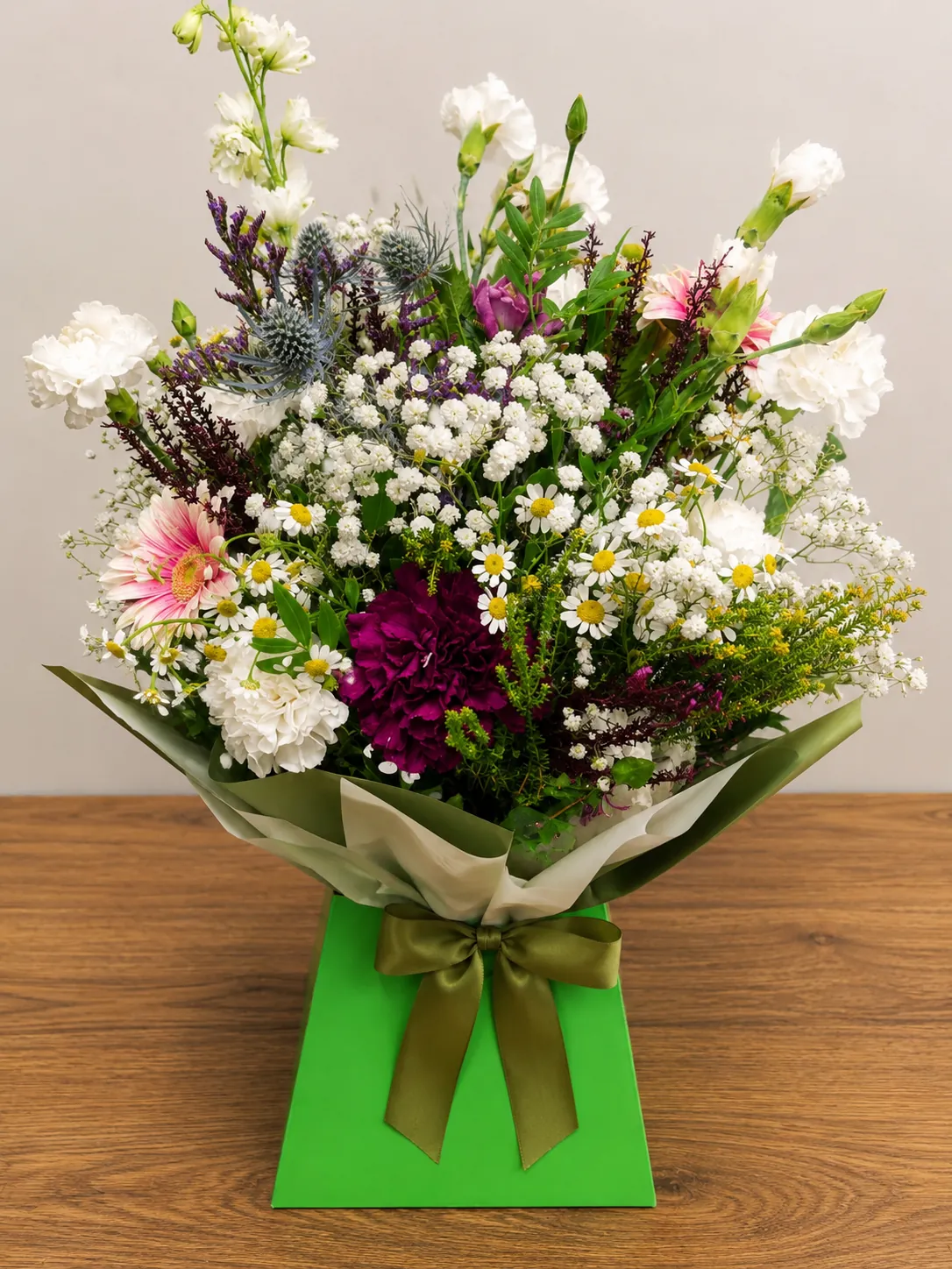 Wildflower-style box arrangement with white carnations, gypsophila and chamomile daisies in a green gift box