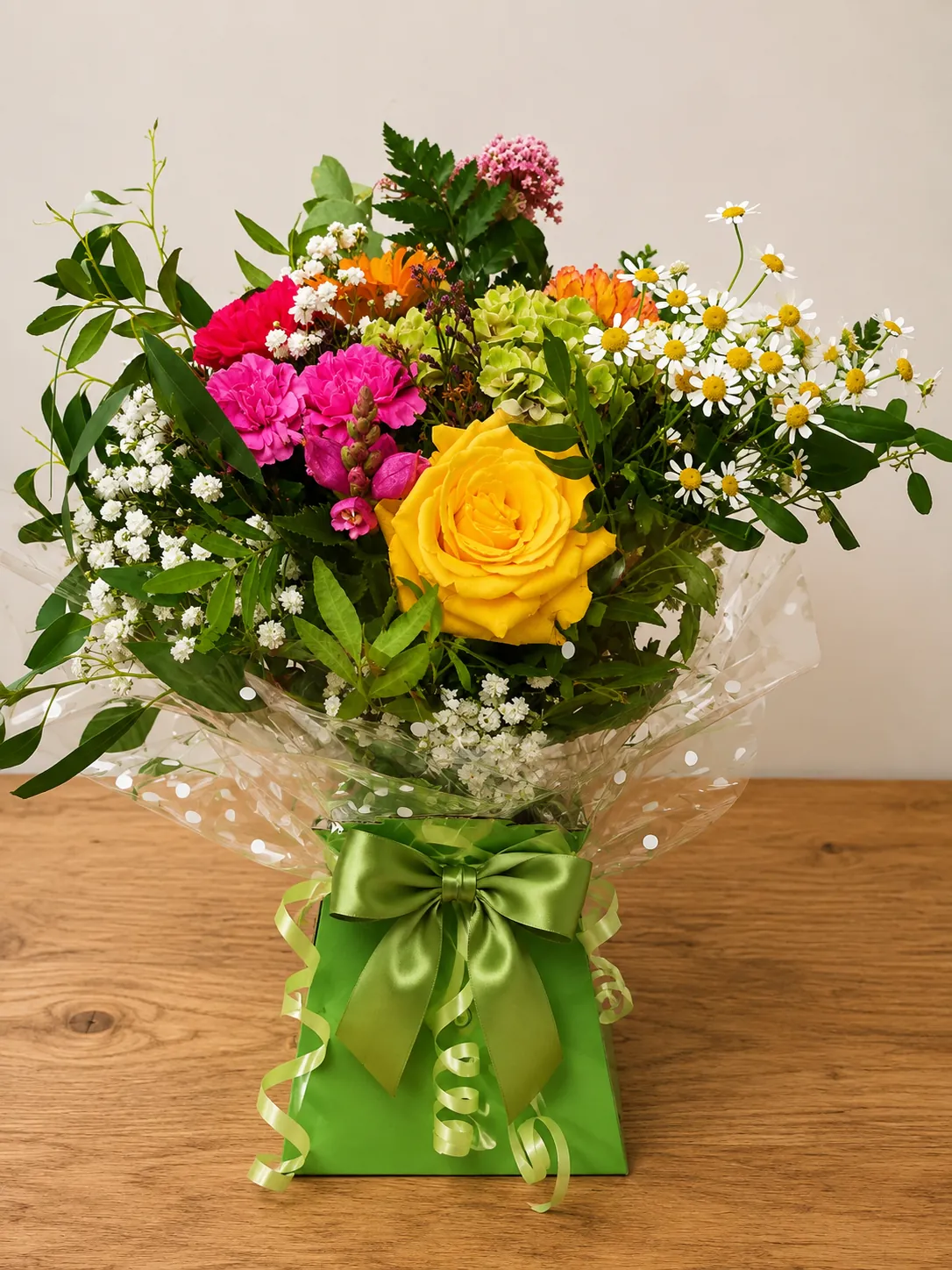 Colourful box arrangement with a yellow rose, pink carnations and chamomile daisies in a green gift box
