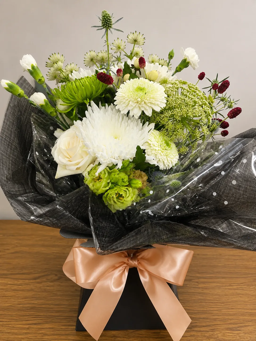 White and green box arrangement with chrysanthemum, astrantia and gypsophila in a black gift box with a peach bow