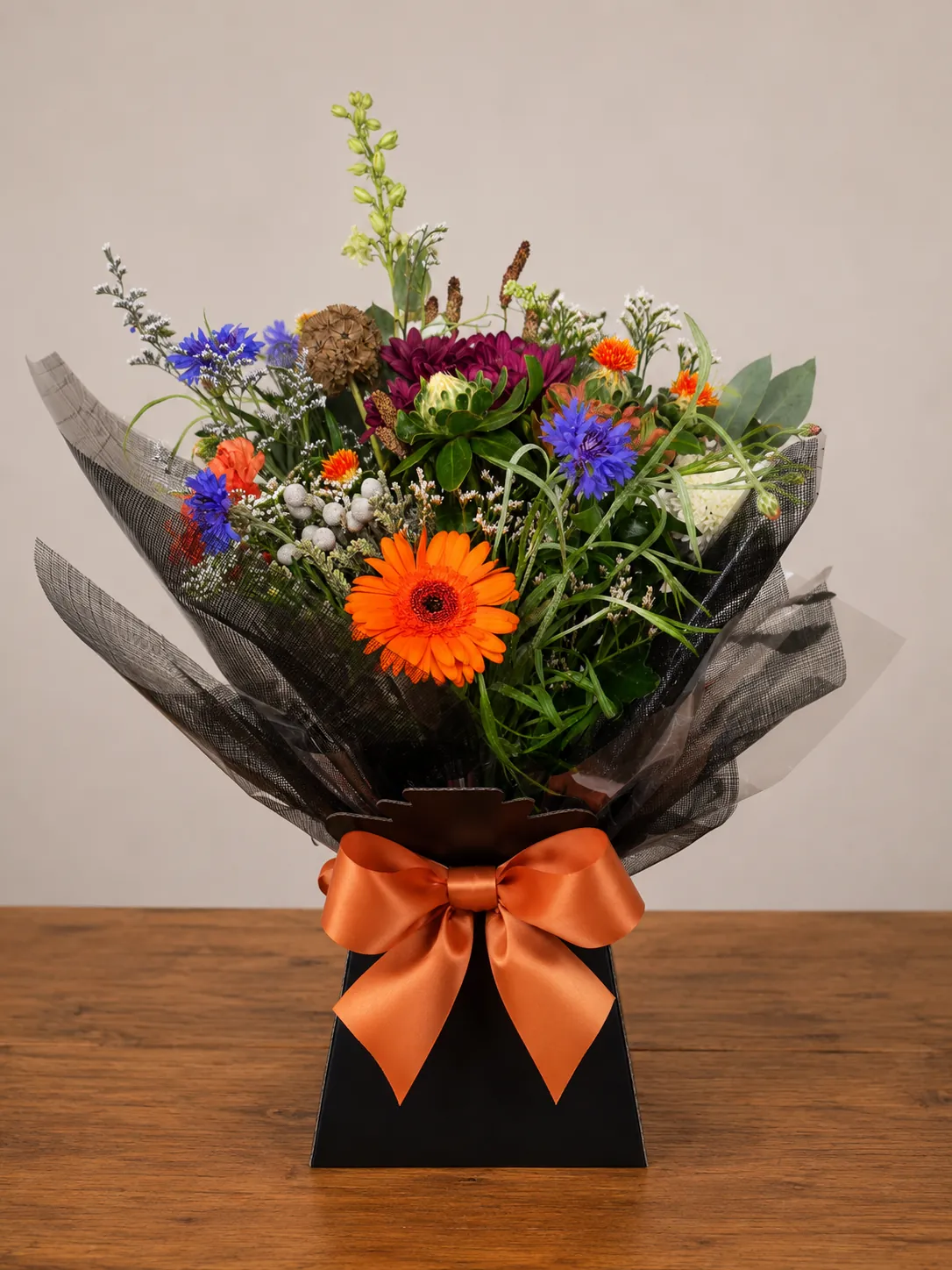 Autumn-toned box arrangement with white chrysanthemum and blue cornflower