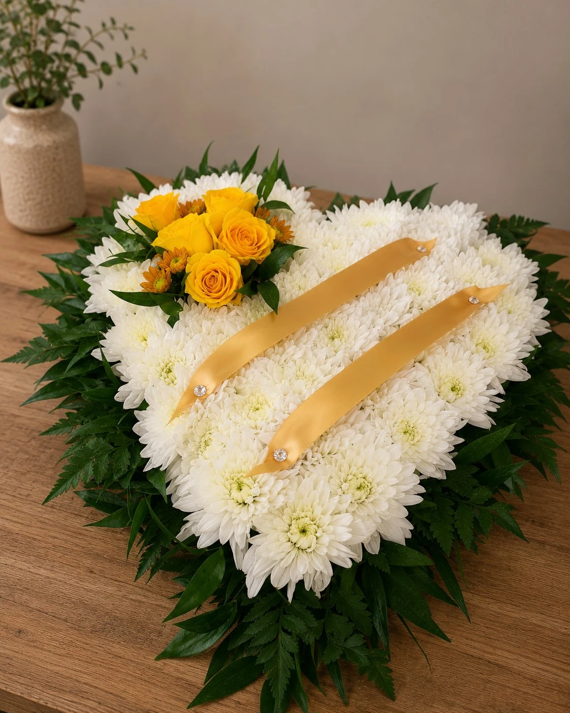 White heart-shaped funeral tribute with yellow roses by Quality Plants and Flowers