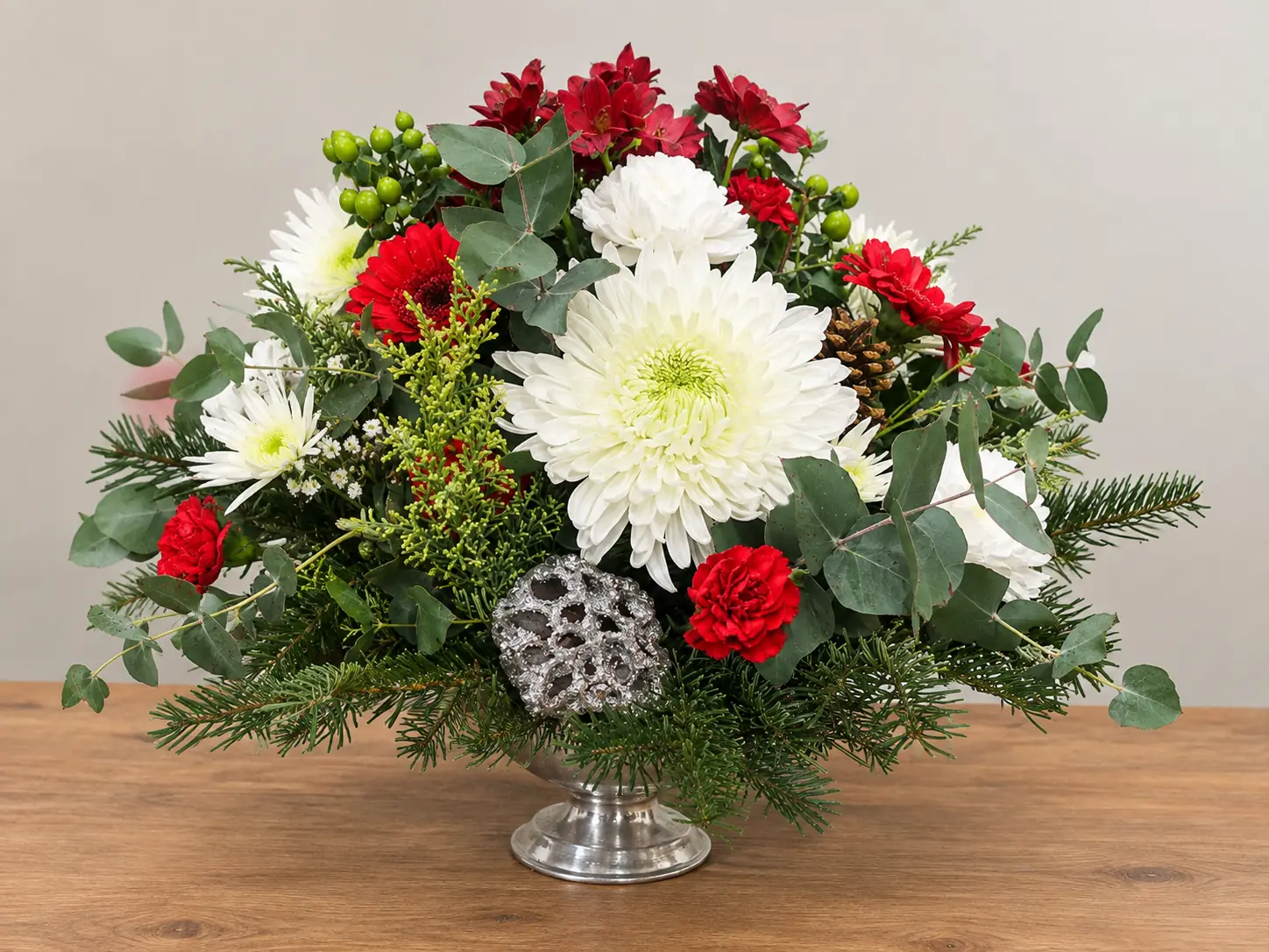 Footed bowl Christmas table arrangement with red flowers, pinecones and foliage
