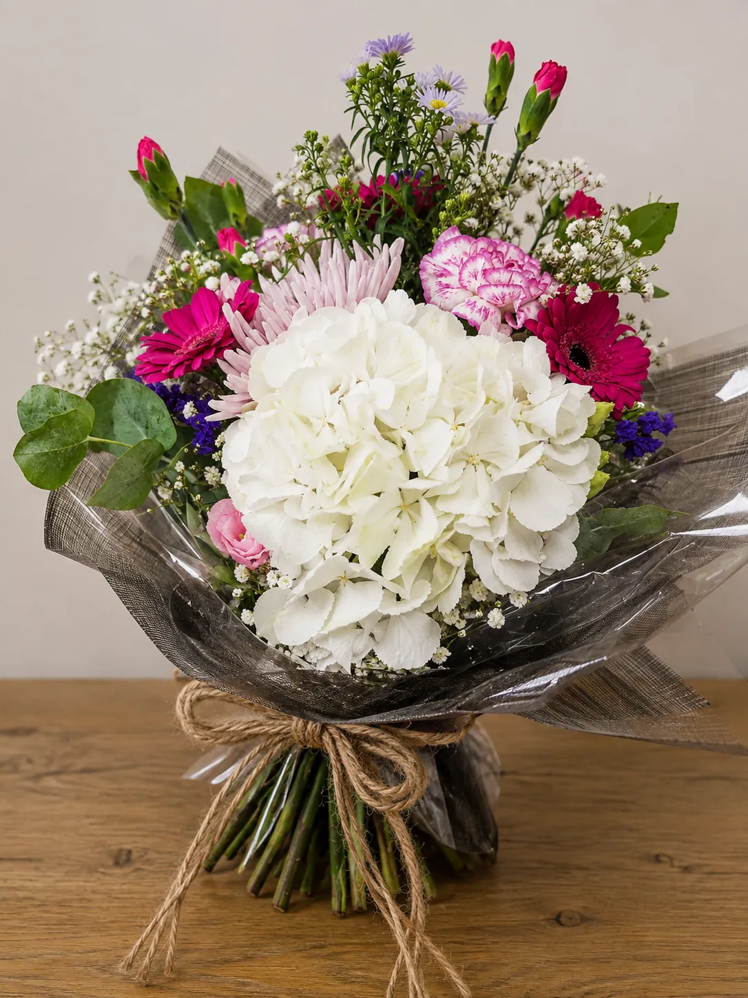 White hydrangea hand-tied bouquet with pink gerbera and carnations, tied with rustic twine