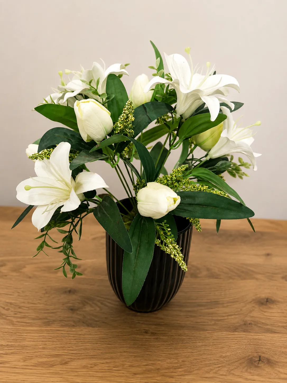 White lily arrangement in a black ribbed ceramic vase