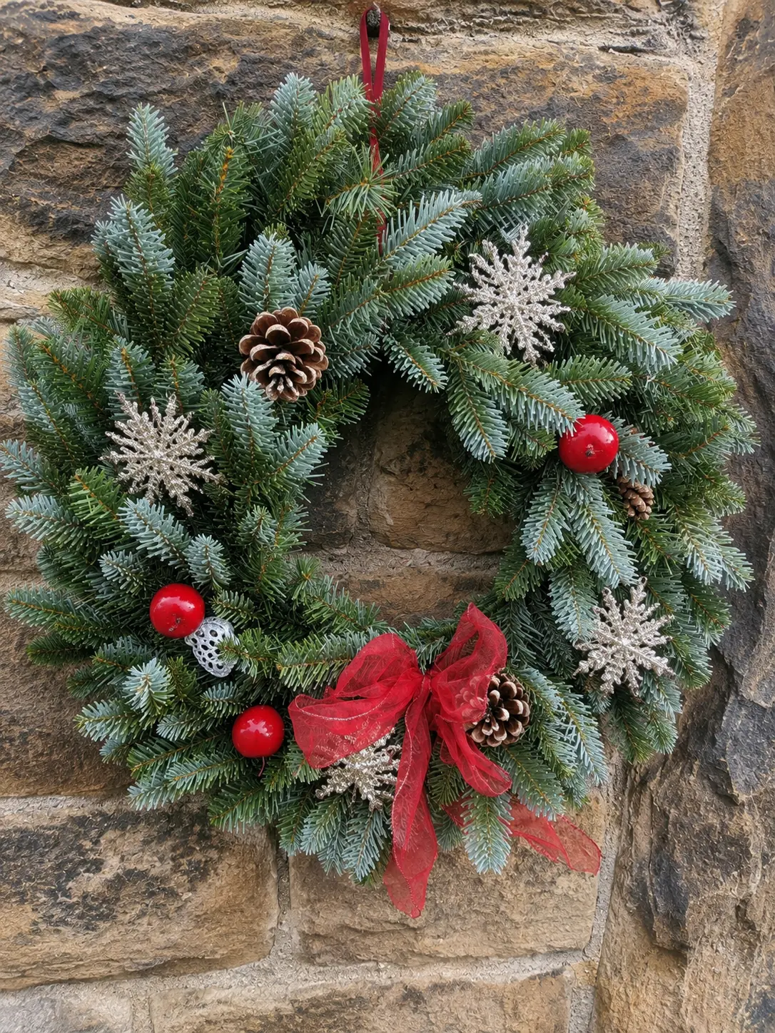 Christmas wreath with snowflake decoration displayed on a stone wall