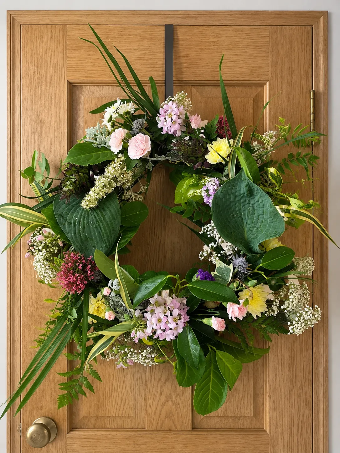Pastel flower sympathy wreath displayed on a front door