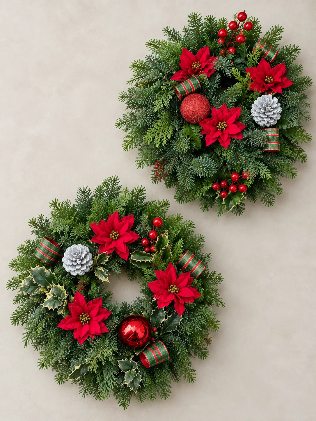 Pair of red poinsettia plants and a Christmas wreath arranged together